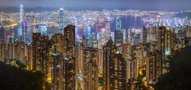 Victoria Harbour and the Hong Kong Island skyline lit at night, seen from the Tsim Sha Tsui waterfront